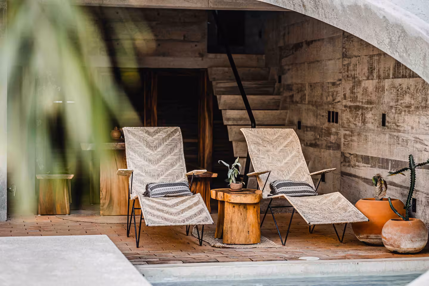 Brutalist Casa Hezbo Airbnb in Puerto Escondido with circular concrete pool opening, private swimming pool, tropical greenery, and open-air lounge area.
