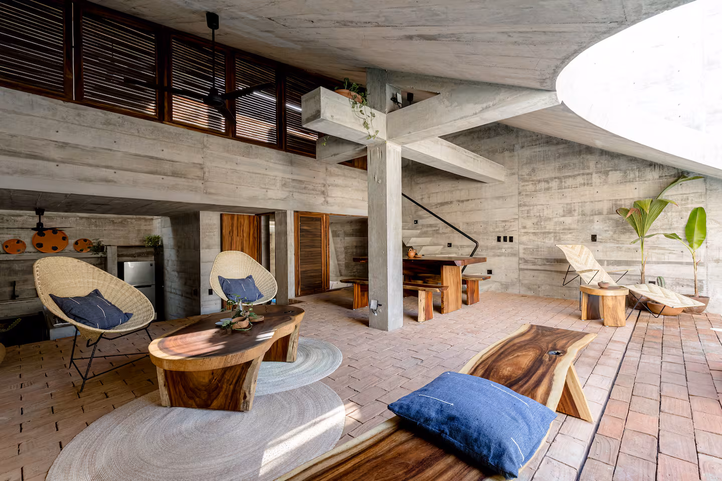 Brutalist Casa Hezbo Airbnb in Puerto Escondido with circular concrete pool opening, private swimming pool, tropical greenery, and open-air lounge area.