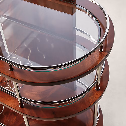 Ralph Lauren Home Duke Bar Cart with polished stainless steel frame, mahogany handle, glass shelves, casters, and bottle storage for a luxury home bar.