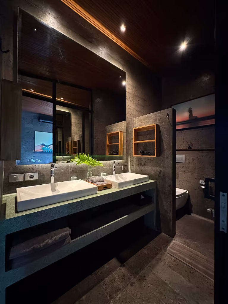 Interior of Alpha House Bali featuring curved wooden ceilings, locally crafted teak furniture, Indonesian art and open views of Ubud’s tropical landscape.