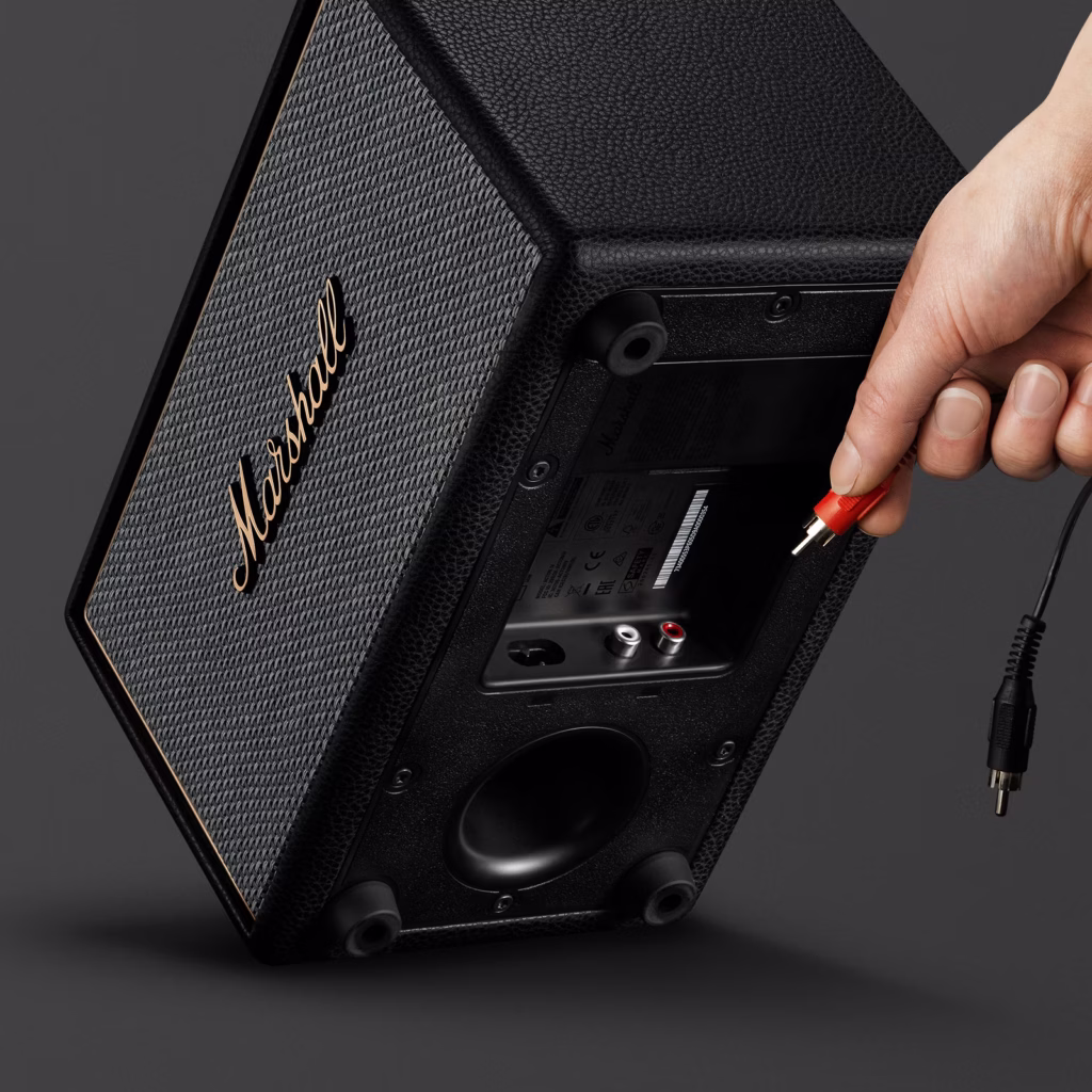 Marshall Acton IV wireless speaker in black with gold accents against a dark background.
