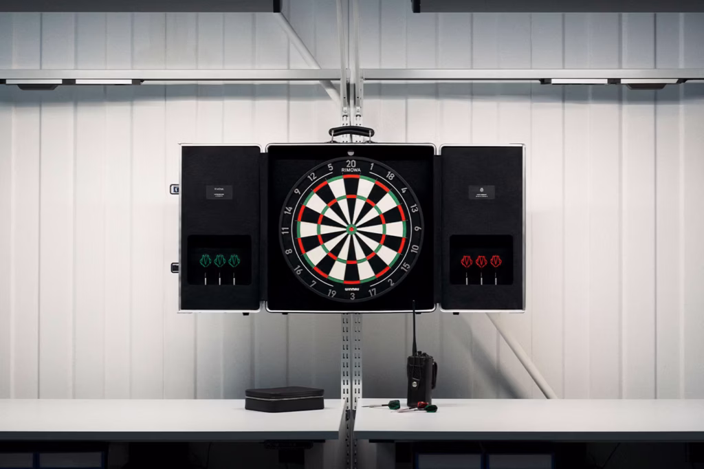 RIMOWA Dartboard Case by Winmau displayed in a clean industrial interior, showcasing the luxury aluminum cabinet, professional Blade X dartboard, integrated storage compartments, and signature RIMOWA design language.