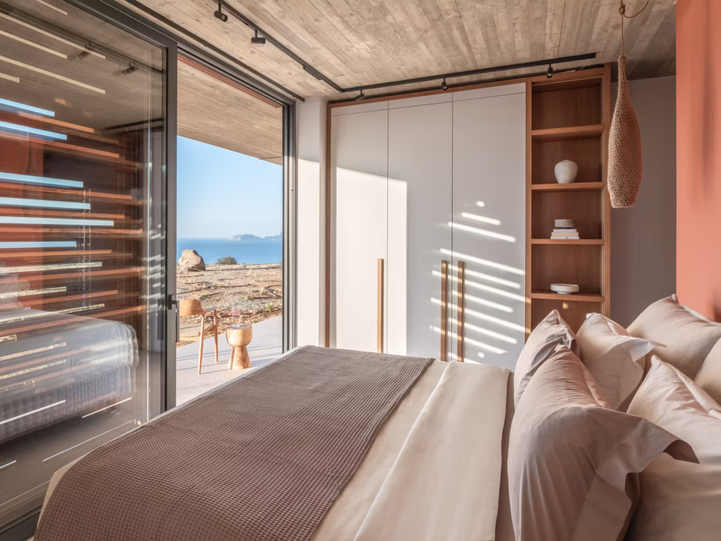 Bedroom inside Keras Cliff House with warm wood details and views toward the Libyan Sea