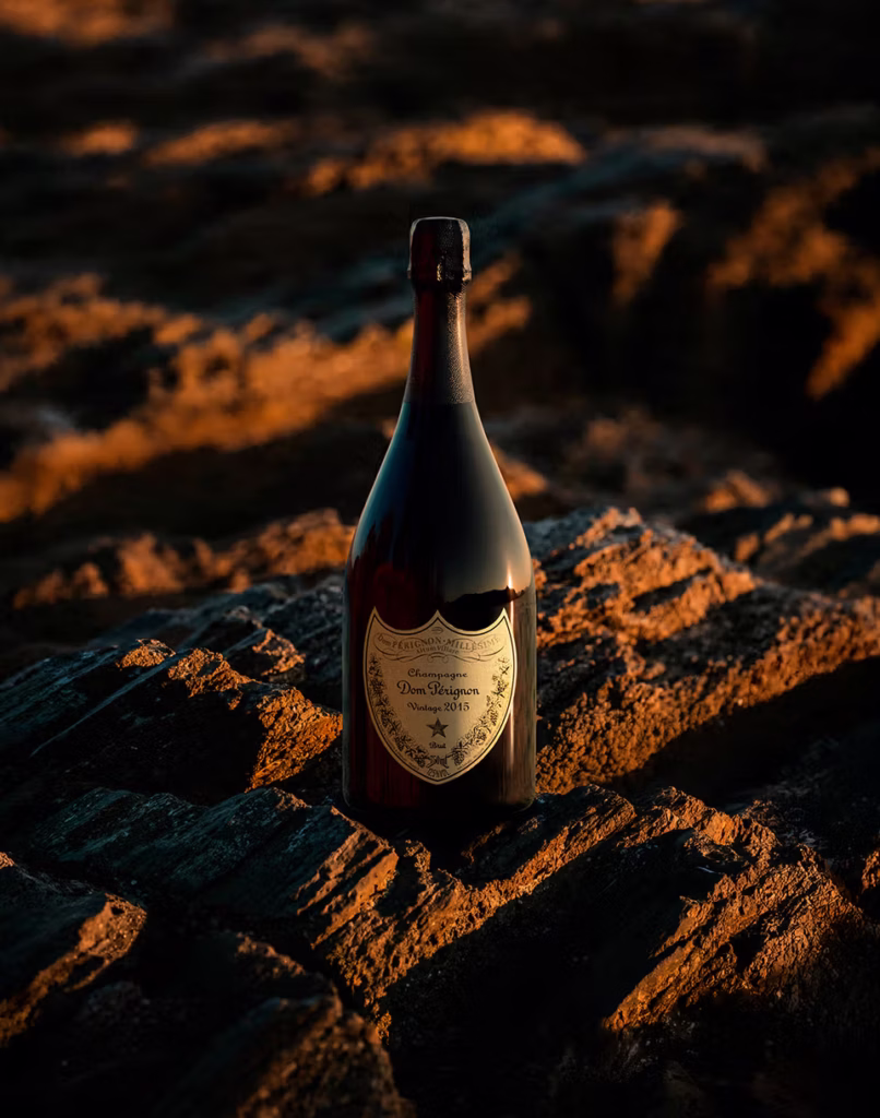 Dom Pérignon Vintage 2015 Champagne bottle photographed among sunlit rocks