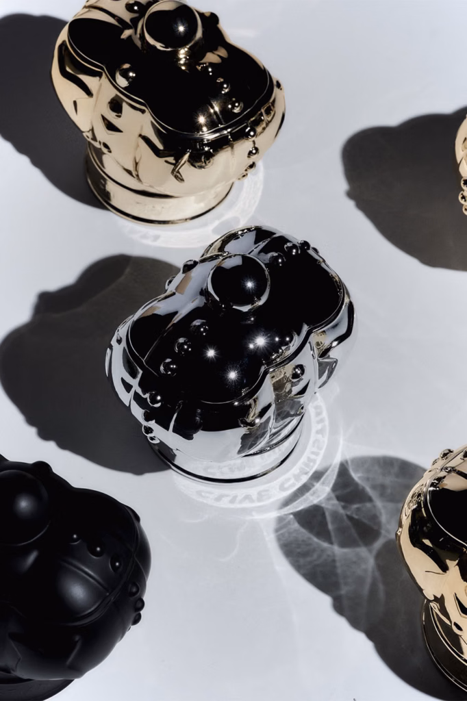 Black, silver and gold Clive Christian Fine Objects vessels arranged under dramatic lighting and shadows.