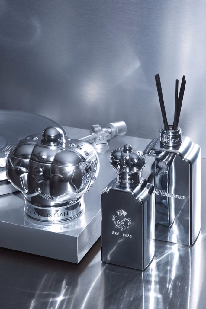 Clive Christian Fine Objects silver candle and fragrance diffusers displayed beside a metallic turntable in a reflective studio setting.