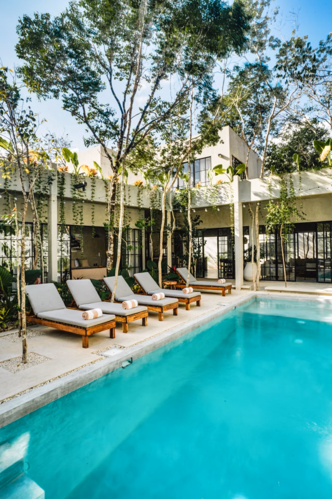Contemporary exterior of Villa Arthur 600 overlooking a turquoise swimming pool, wooden lounge chairs and lush tropical landscaping.